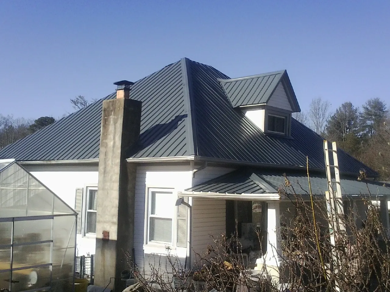 Dark blue standing seam metal roof on a white farmhouse with dormer — Slate & Tile Roof Repair by Roofing Brothers in Slatington