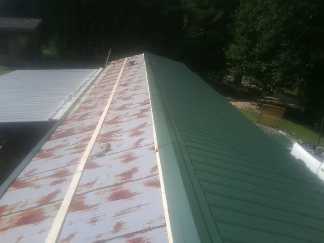 Old rusted panels beside newly installed green metal roofing — Wind Damage Roof Repair by Roofing Brothers in Slatington