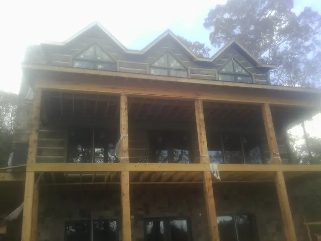 Dormers and porch framing on a large log home under construction — Roof Coating work by our crew in Slatington