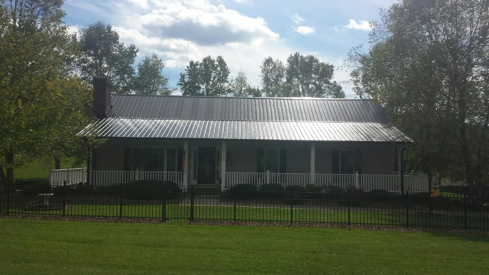 Gray metal roof on a brick ranch with a full width front porch — Gutter Guard Installation work by our crew in Slatington