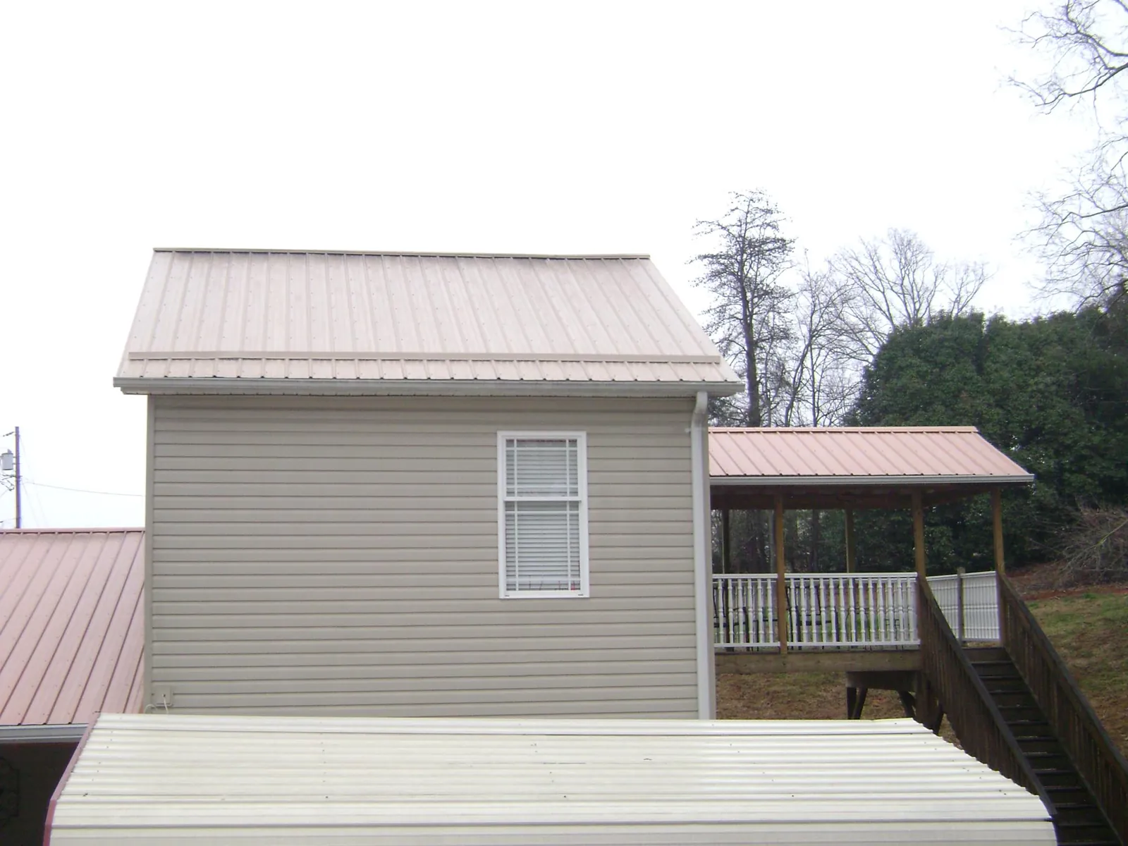 Tan metal roofs on a two story addition and attached porch, from a Roof Replacement job in Slatington